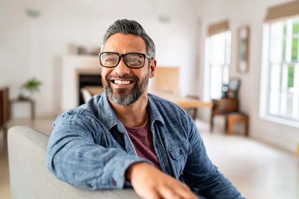 An older man smiles as he sits in a stylish living room