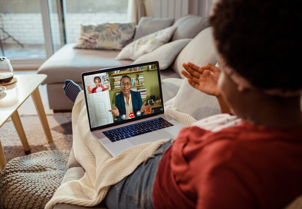 Young woman talking to her therapist online Young woman laying on sofa talks to her online therapist