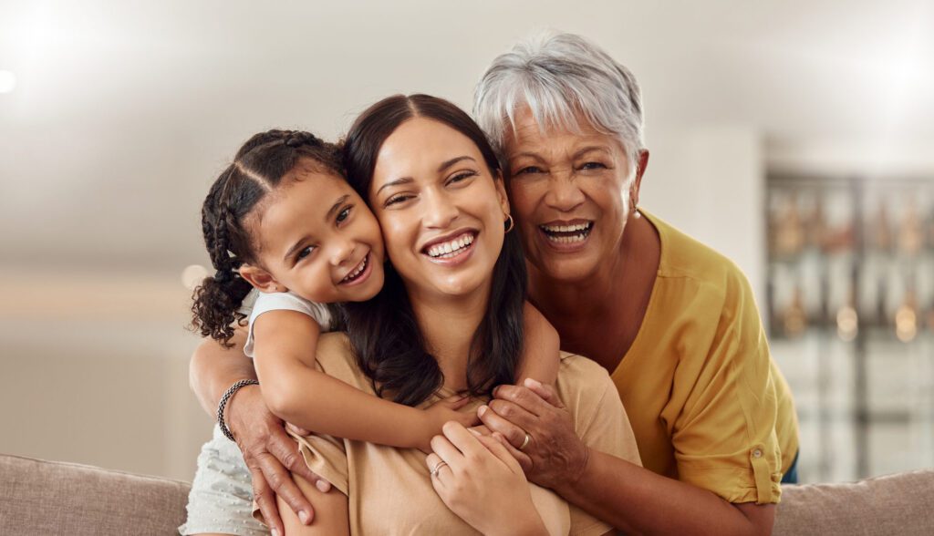 Three generations of women, a daughter, mother and grandmother, smile and embrace each other